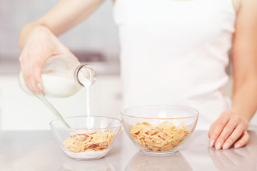 Female pouring milk in plate with oak flakes.