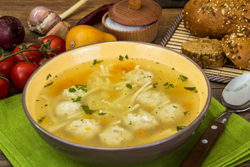 Broth with chicken meatballs and noodles in ceramic bowl