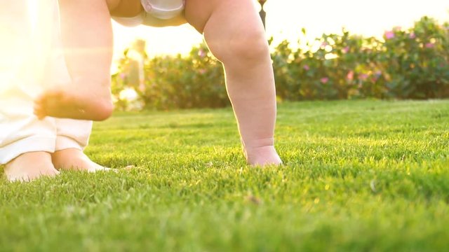 Baby girl doing first steps with mothers help