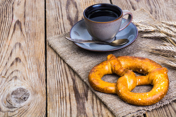 Pretzels with salt and black coffee on wooden background