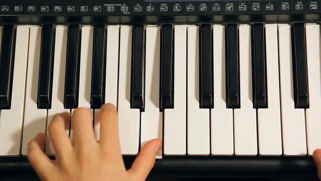 Child boy playing on an electronic keyboard instrument. Gifted kid