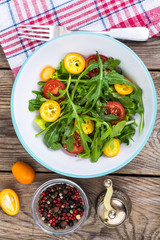 Vegetarian salad with arugula, kumquats and tomatoes