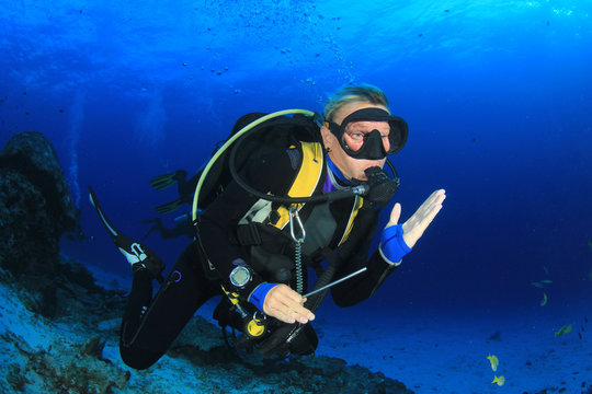 Blonde woman scuba diver explore coral reef in ocean