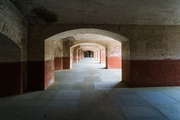 Masonry arched hallway stretching away into the darkness. Typical of forts and prisons of the Victorian period