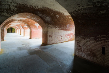 Masonry arched hallway stretching away into the darkness. Typical of forts and prisons of the Victorian period