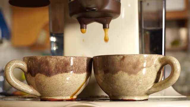 Making espresso coffee in coffeemaker machine in home kitchen, closeup. 4K ProRes HQ codec