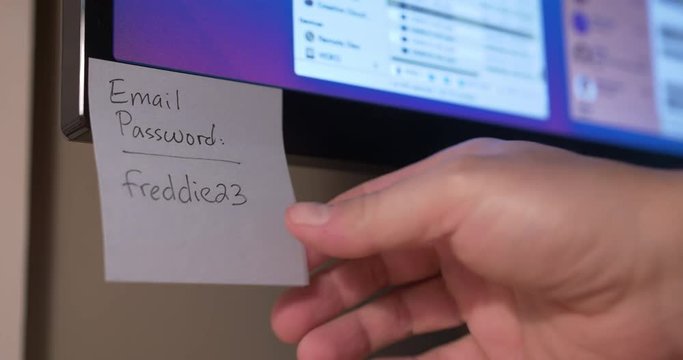 A person removes Post-It password reminders from a computer monitor.	 	
