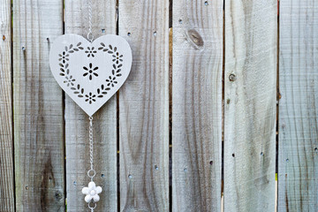 Background - Decorative silver metal heart hanging on grey wooden fence
