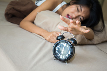 Happy young asian woman angry with clock when wake up on morning.