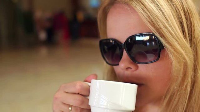 Girl in sunglasses drinks coffee, slow motion. Portrait of a girl with a cup of coffee.