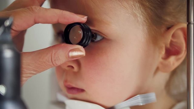 Child's ophthalmology - doctor optometrist checks eyesight for little girl