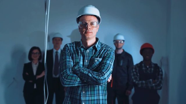 The adult taskmaster standing at the builders team and holding arms crossed.