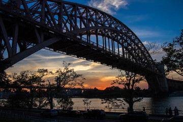 Hell Gate Bridge and in silhouette with sunset sky, New York