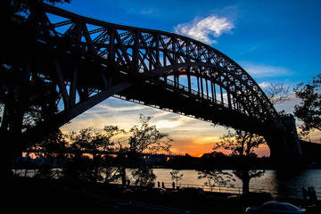 Hell Gate Bridge and in silhouette with sunset sky, New York