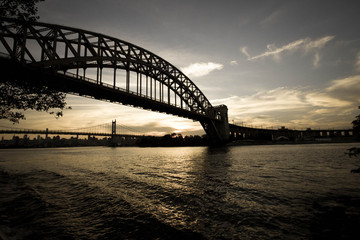 Dark Silhouette of Hell Gate Bridge and Triborough bridge over the river in vintage style, New York