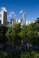 Fototapeta premium Reflective lake under the shade and buildings in Manhattan