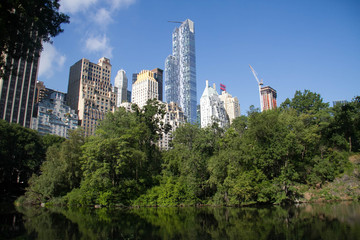 Fototapeta premium Reflective lake under the shade and buildings in summertime, Manhattan