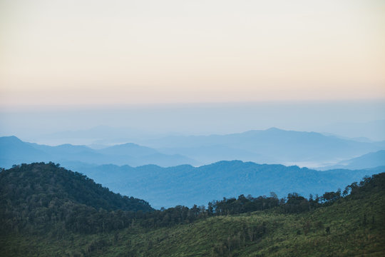 Beautiful autumnal landscape with sunrise over a foggy valley and mountain ranges.