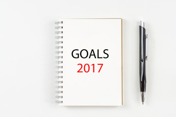 Top view 2017 goals list with notebook, pen on white background.
