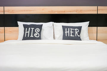 his and her word stylish bedroom interior design with black patterned pillows on bed and decorative table lamp.selective focus