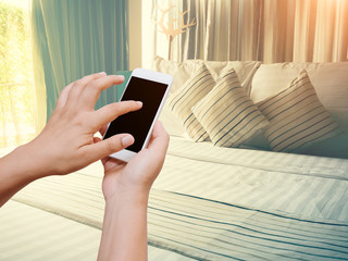 Woman hand hold and touch screen smart phone on vintage bedroom in the morning.