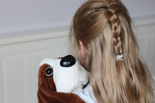 Lonely blond hair girl with plush dog in arms