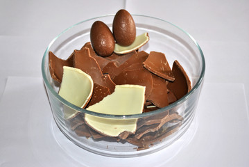 Easter Eggs chocolate. Cracked Eggs chocolate of glass container, white background. Milk and White chocolate