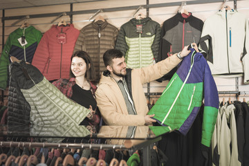 Young smiling couple choosing on windcheater