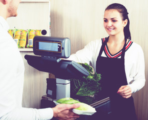 Female seller helping customer to weigh cabbage