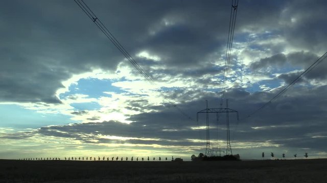 Beautiful sunset over Hane over farmland, trees and the horizon combine harvester and tractor, high voltage wires in Cenral Moravia, Czech Republic, Europe