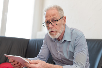 Fototapeta premium Portrait of senior man using a tablet