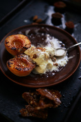 still life with grilled peaches, almonds and ice cream on a dark stone texture