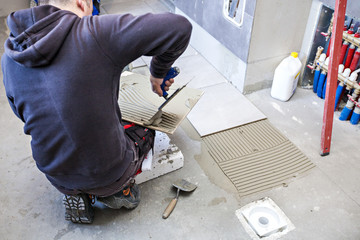Man Tiling  Bathroom. Laying tiles on the floor.