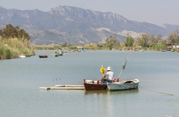 Fototapeta na wymiar Fisherman on a boat. Fresh water lagoon in Estany de cullera. Valencia, Spain