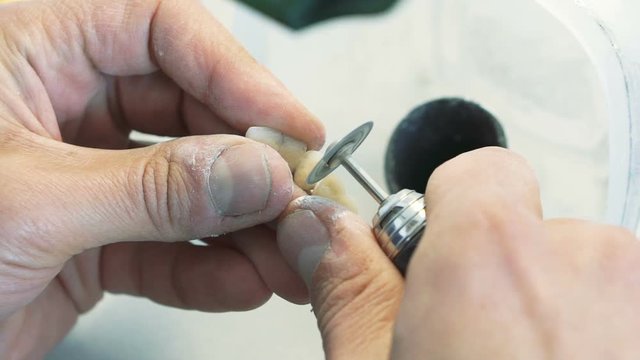 Closeup of grinding teeth crowns with instruments in dental lab