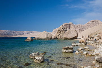 Beautiful sand beach with big rocks in the sea and turquise blue water - sea water background