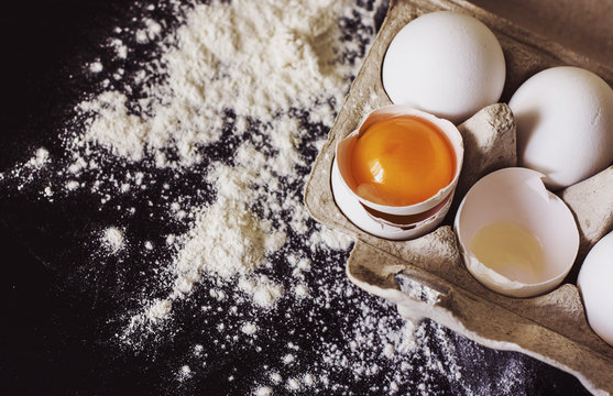 Eggs and flour on dark table