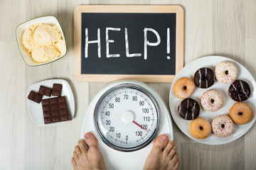 Man Measuring His Weight With Help Sign And Dessert