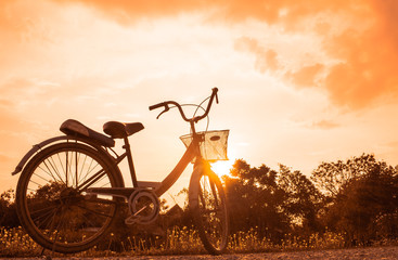Fototapeta na wymiar old bicycle style at summer grass field, beautiful landscape with sunset