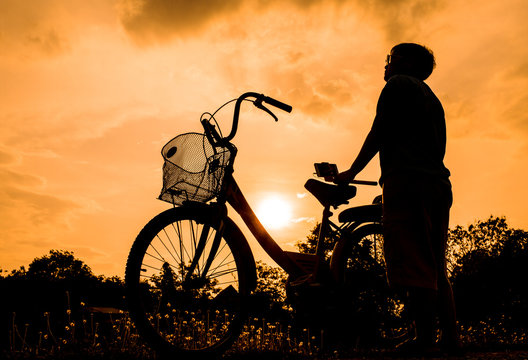 old bicycle style with smart people standing near bike at summer grass field, beautiful landscape with sunset