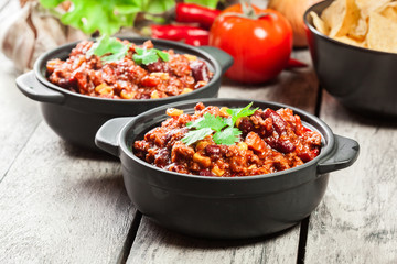 Bowls of hot chili con carne with ground beef, beans, tomatoes and corn - obrazy, fototapety, plakaty