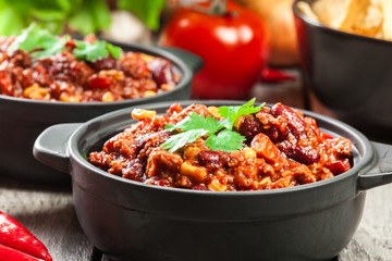 Bowls of hot chili con carne with ground beef, beans, tomatoes and corn
