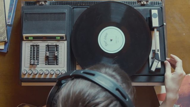 Girl plays vinyl with turntable and listening to music on headphones