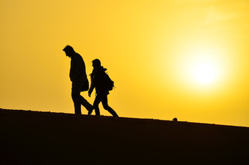 Silhouette of a Man and a Woman Walking on the Sand Dunes of the Sahara Desert During Sunrise