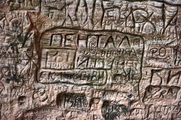 Natural cave in sandstone rock, former bank of Gauja river. Carved wall in Gutmanis cave in Sigulda, Latvia.