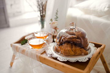 Breakfast with croissants and tea is on the table.