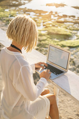 Woman working on laptop in beach bar