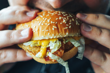 Man holds and bites hamburger