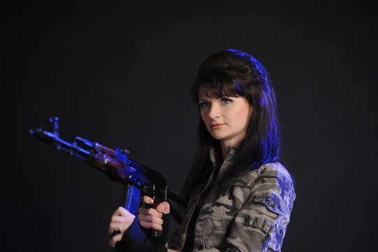 Young pretty female model with AKS-74 (Kalashnikov) assault rifle in studio