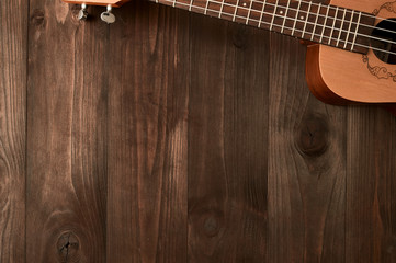 Ukulele lies on a wooden background. Top view. Free space
